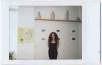 a woman in a black dress standing in front of a shelf